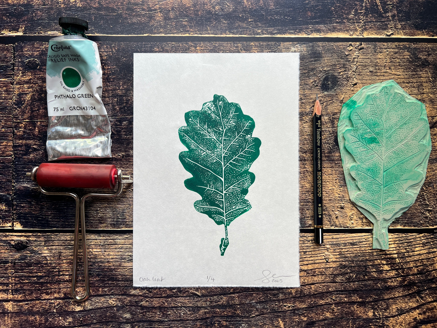 A lino print of an oak leaf in phthalo green.