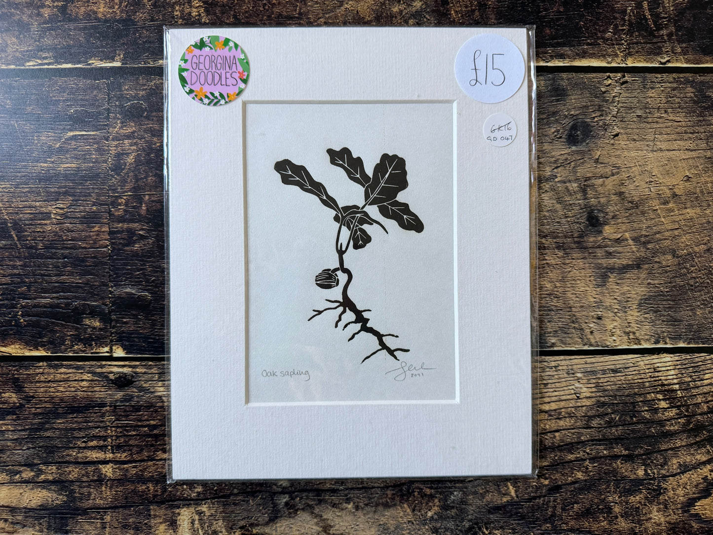 A photograph o f a oak sapling lino print in black, mounted