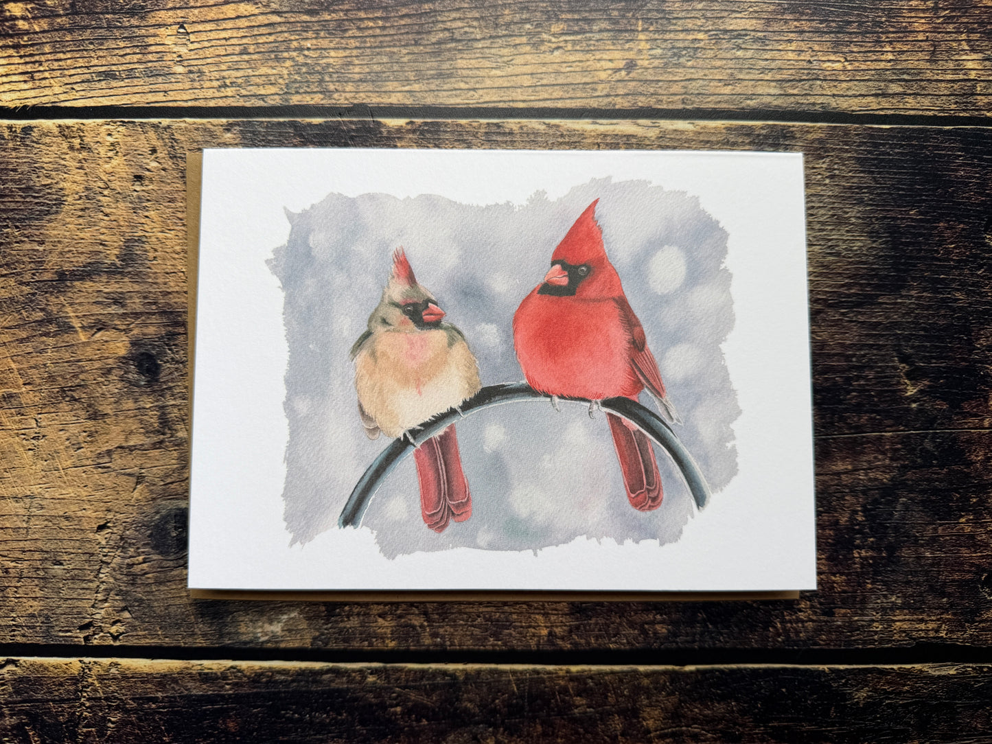 A greetings card with a watercolour print of a pair of cardinals on the front