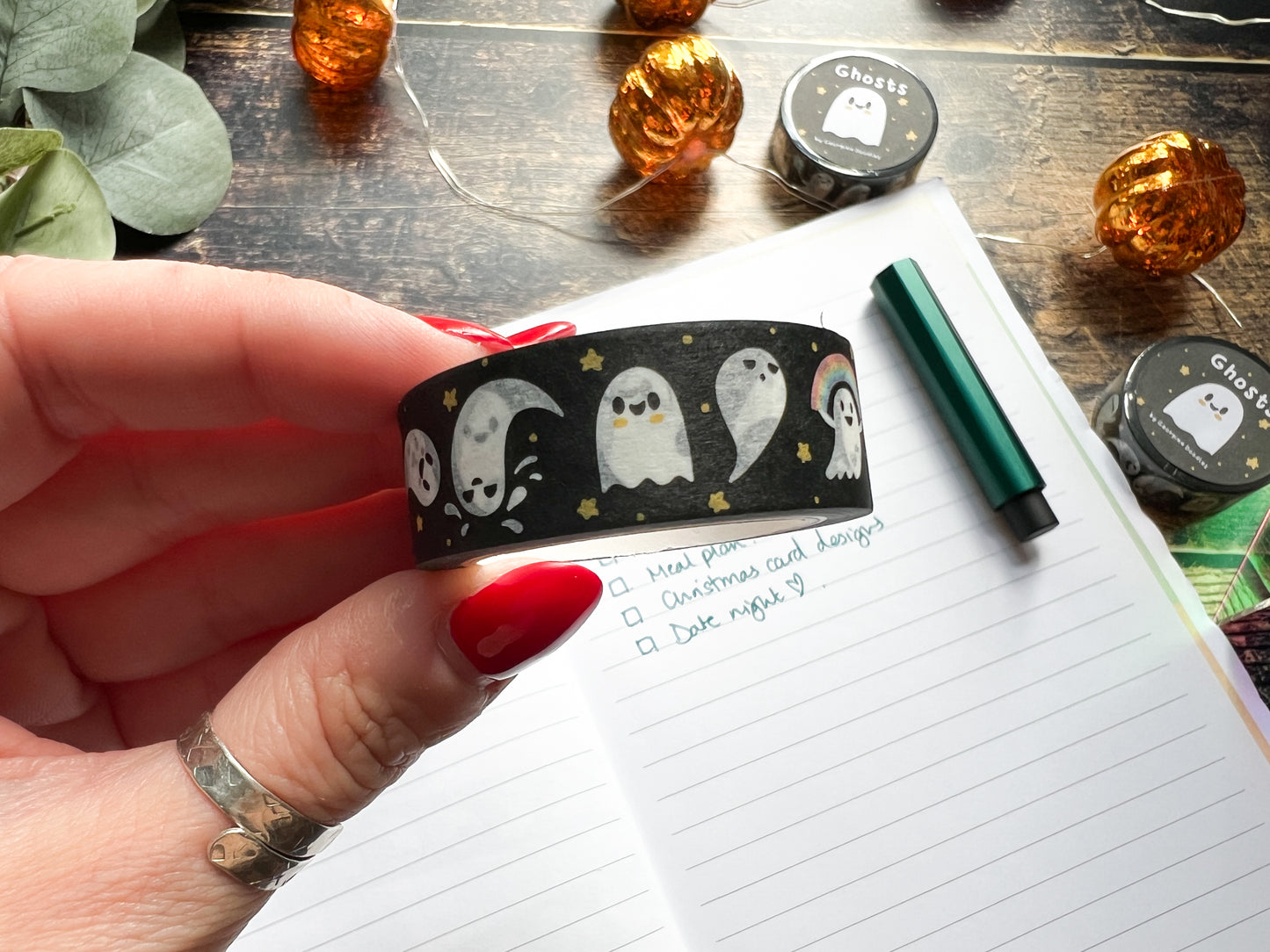 A hand holding a roll of ghost themed washi tape
