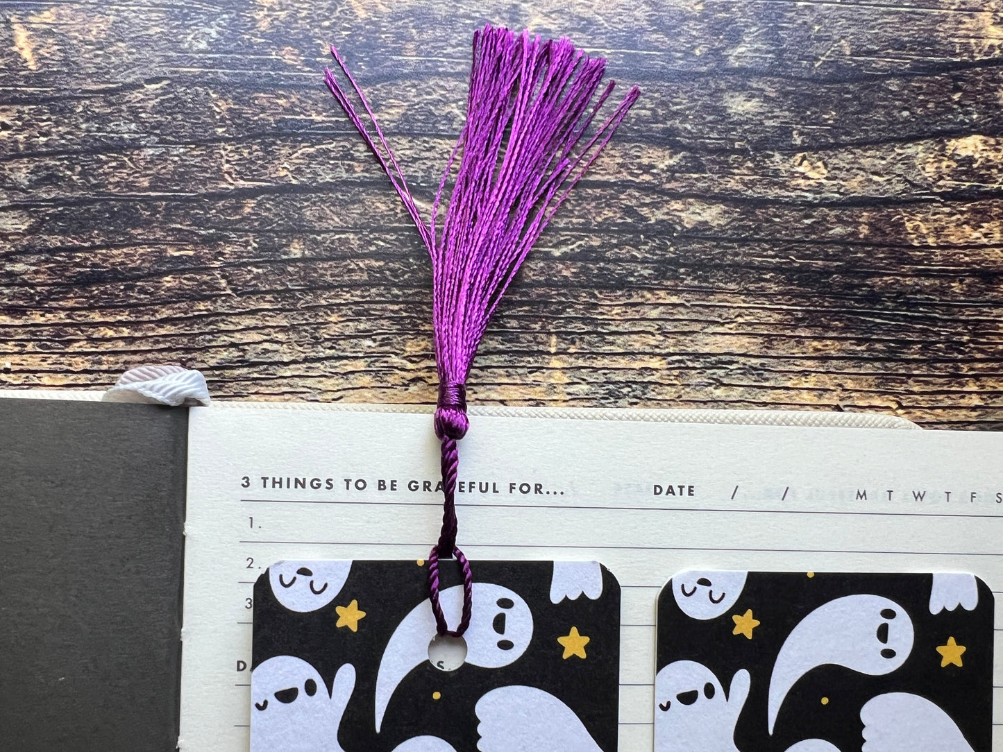 Purple tassel on a planner with ghost designs on a wooden surface