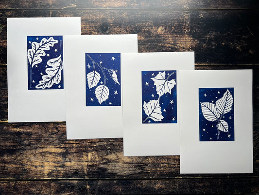 A collection of four lino prints called celestial leaves. They're printed in navy blue and depict leaves surrounded by stars