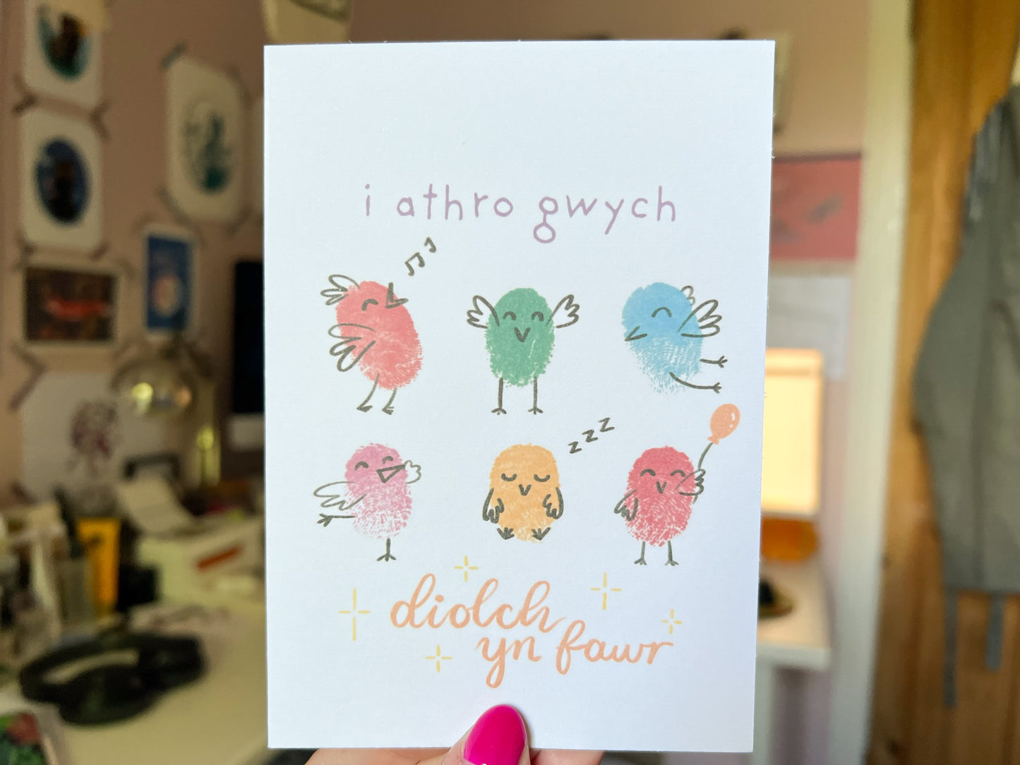 A hand holding a card with six fingerprinted birds on, the card reads 'i athro gwych, diolch yn fawr'.