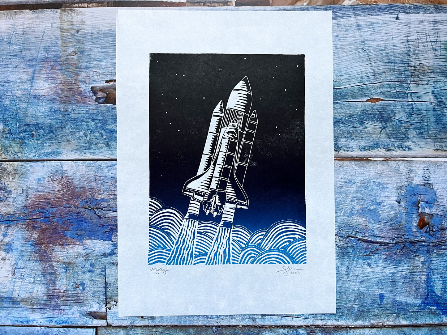 An A4 lino print with a light blue to black gradient or a space shuttled exiting earth's atmosphere