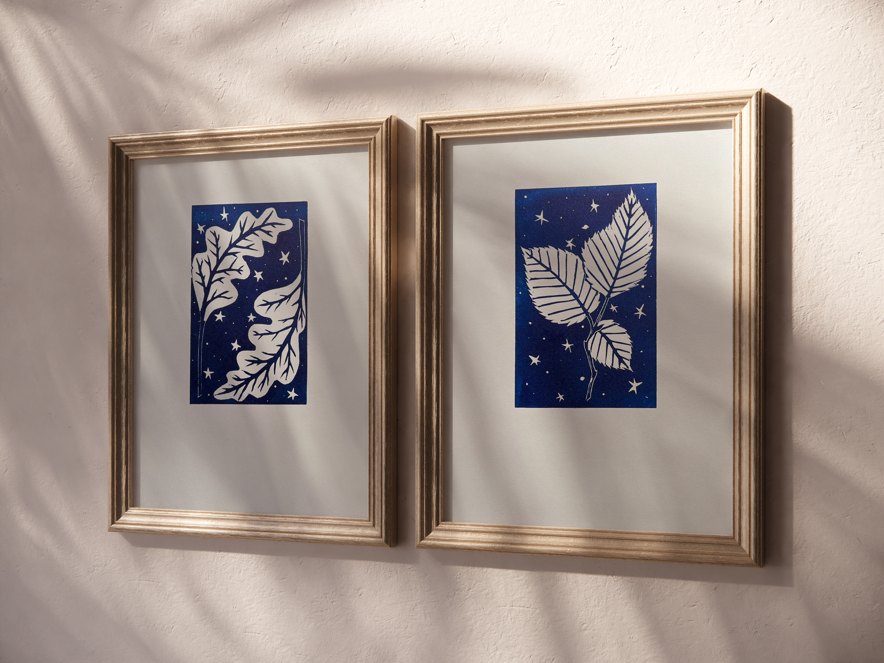 A mockup of two of the prints framed in oak frames on a shadow filled wall