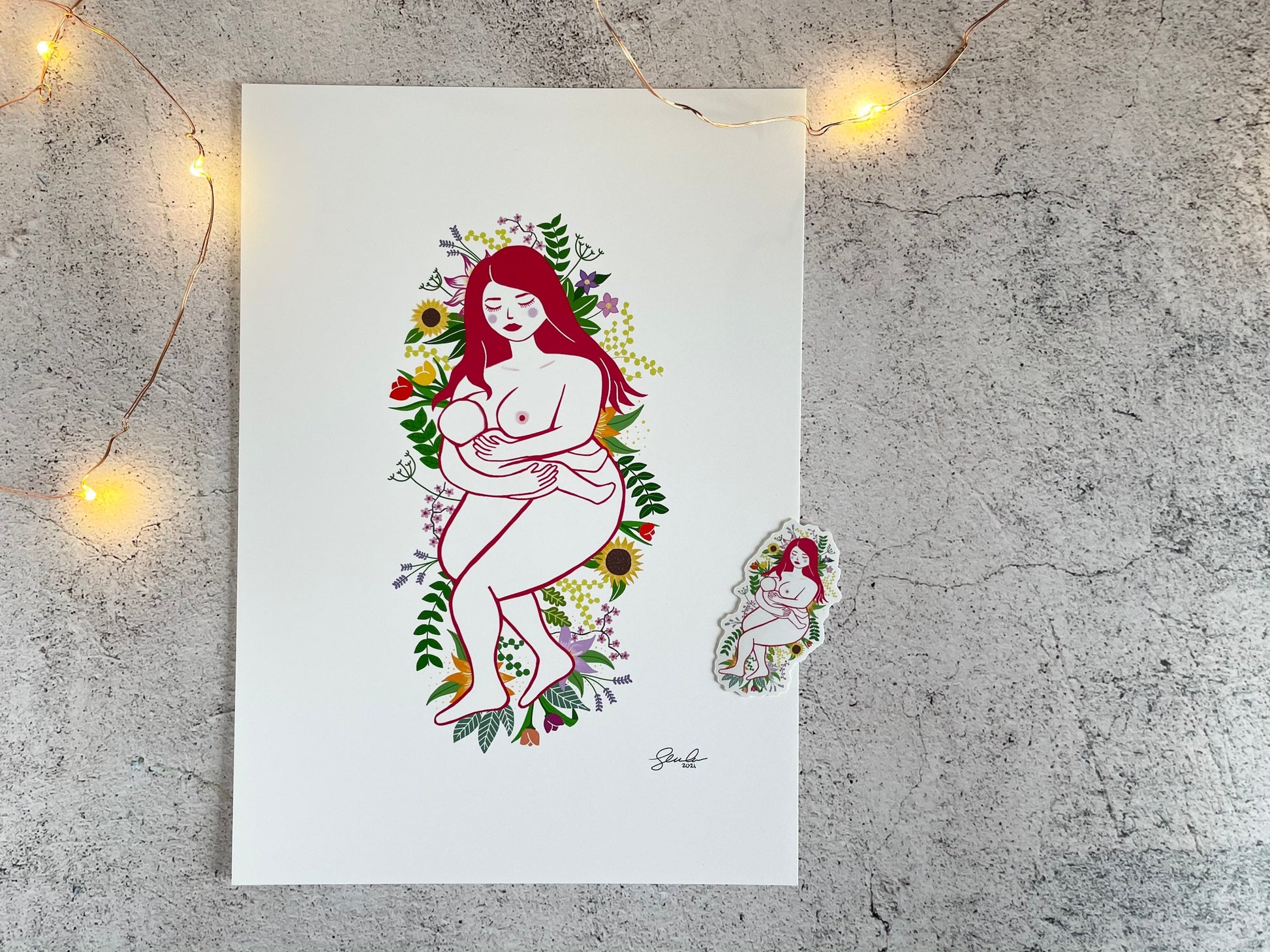 A print and sticker of digital art of a naked mother breastfeeding her baby while laying on a bed of flowers and leaves