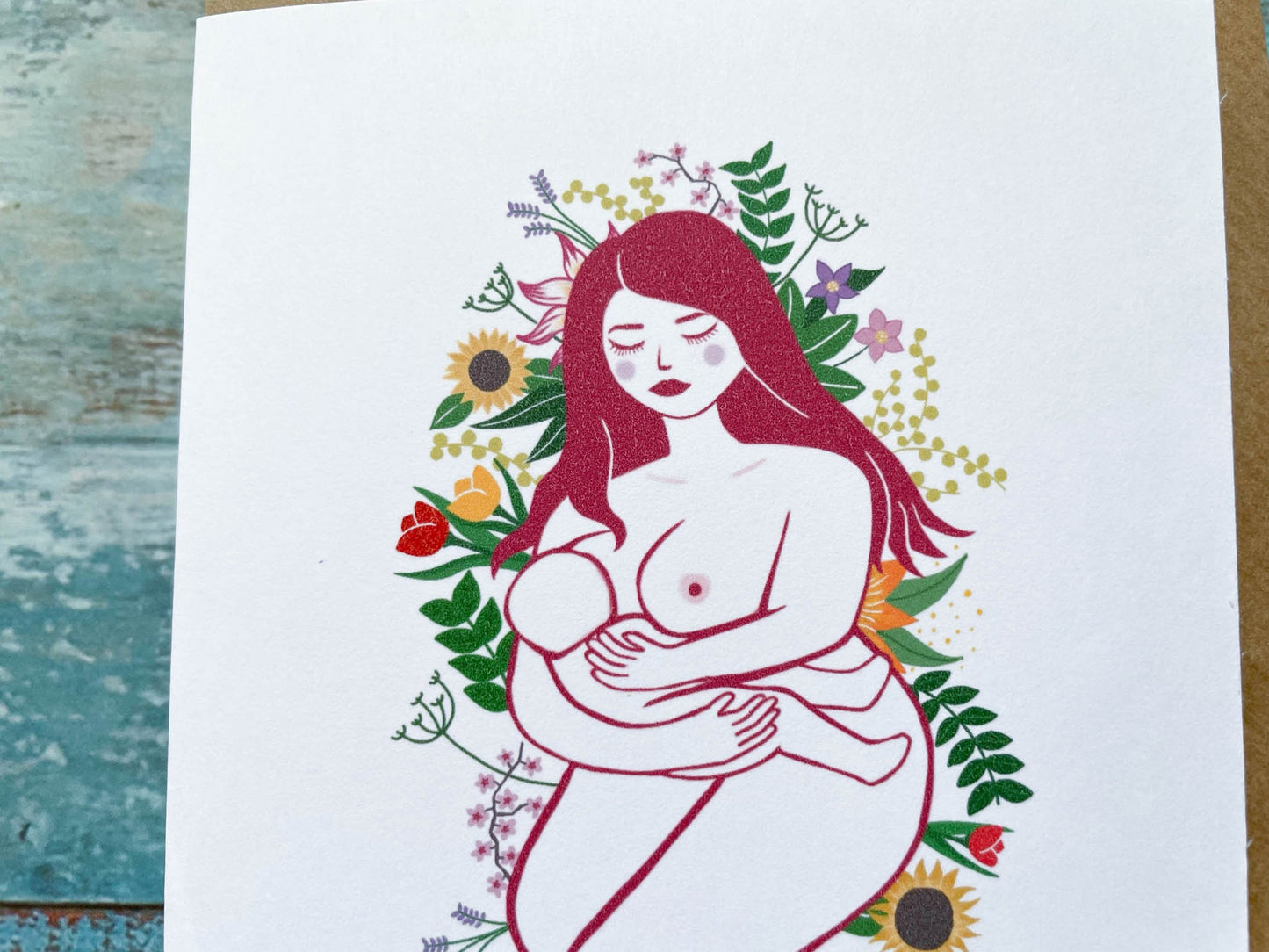 An A6 card of an illustration of a breastfeeding mother laying on a bed of flowers and leaves