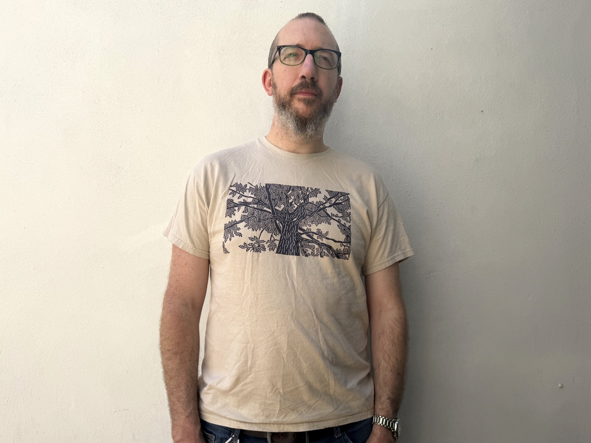 A photo of a man wearing a t-shirt with an oak tree lino print on the front