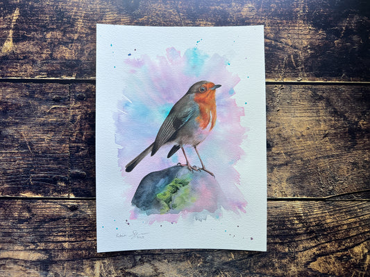 An original watercolour painting of a robin on a rock with a pink and turquoise background
