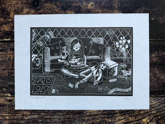 A black & White lino print depicting a mother breastfeeding her baby while her toddler happily plays