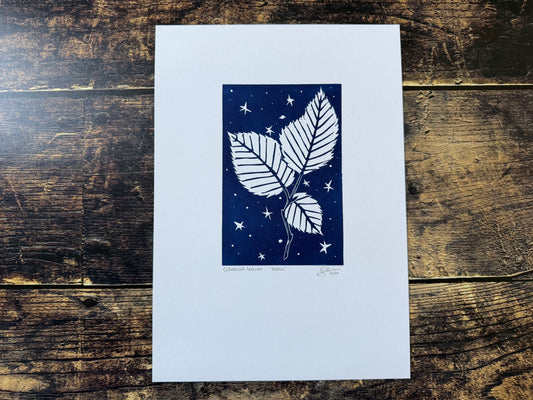 A lino print featuring beech leaves with a night sky behind