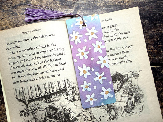 A photo of a watercolour floral bookmark in an open book