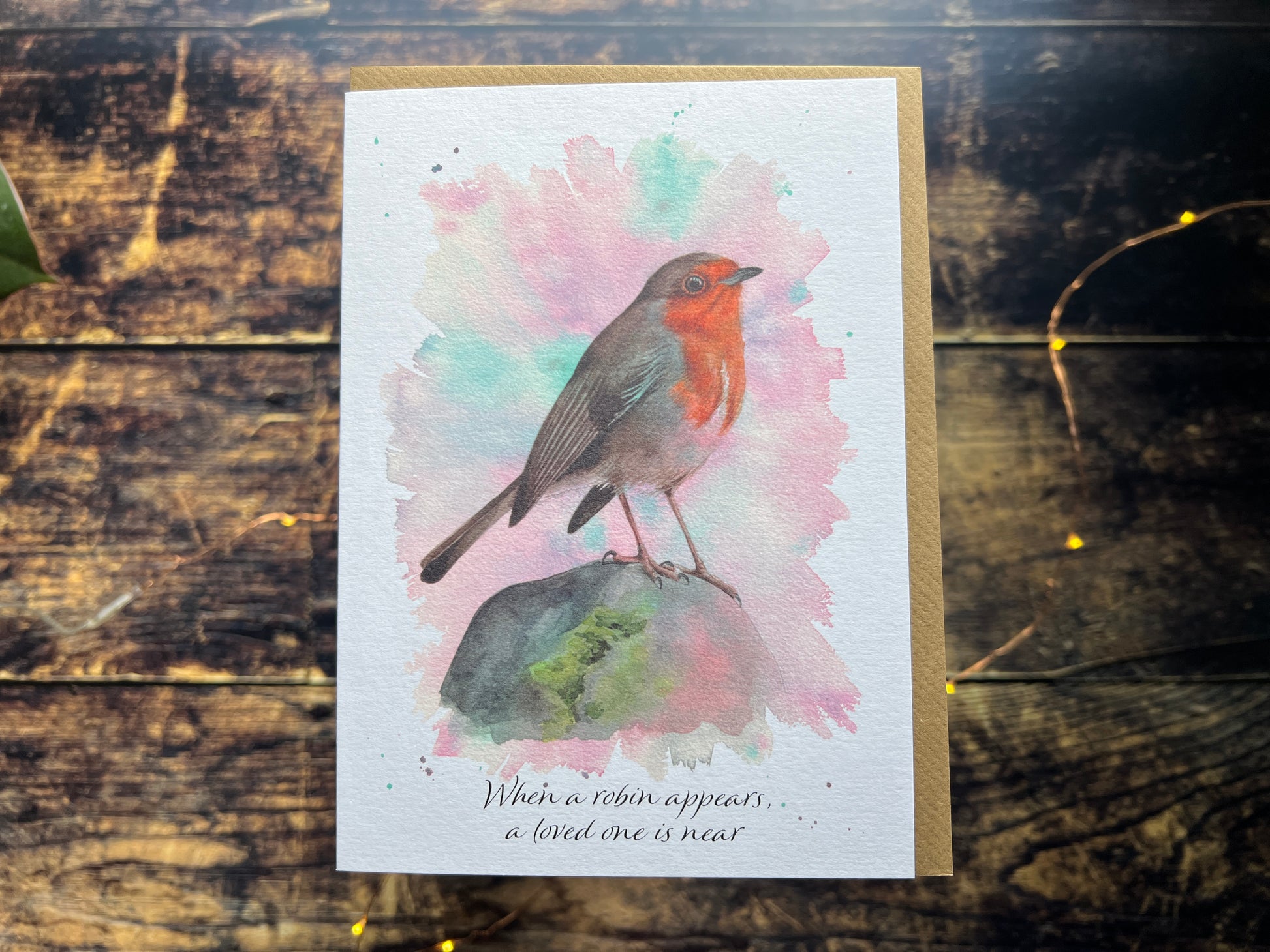 A greetings card featuring a watercolour robin, on the front of the card is says 'When a robin appears, a loved one is near'