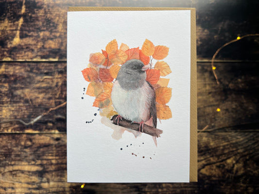A greetings card with a watercolour painting on the front of a dark-eyed junco