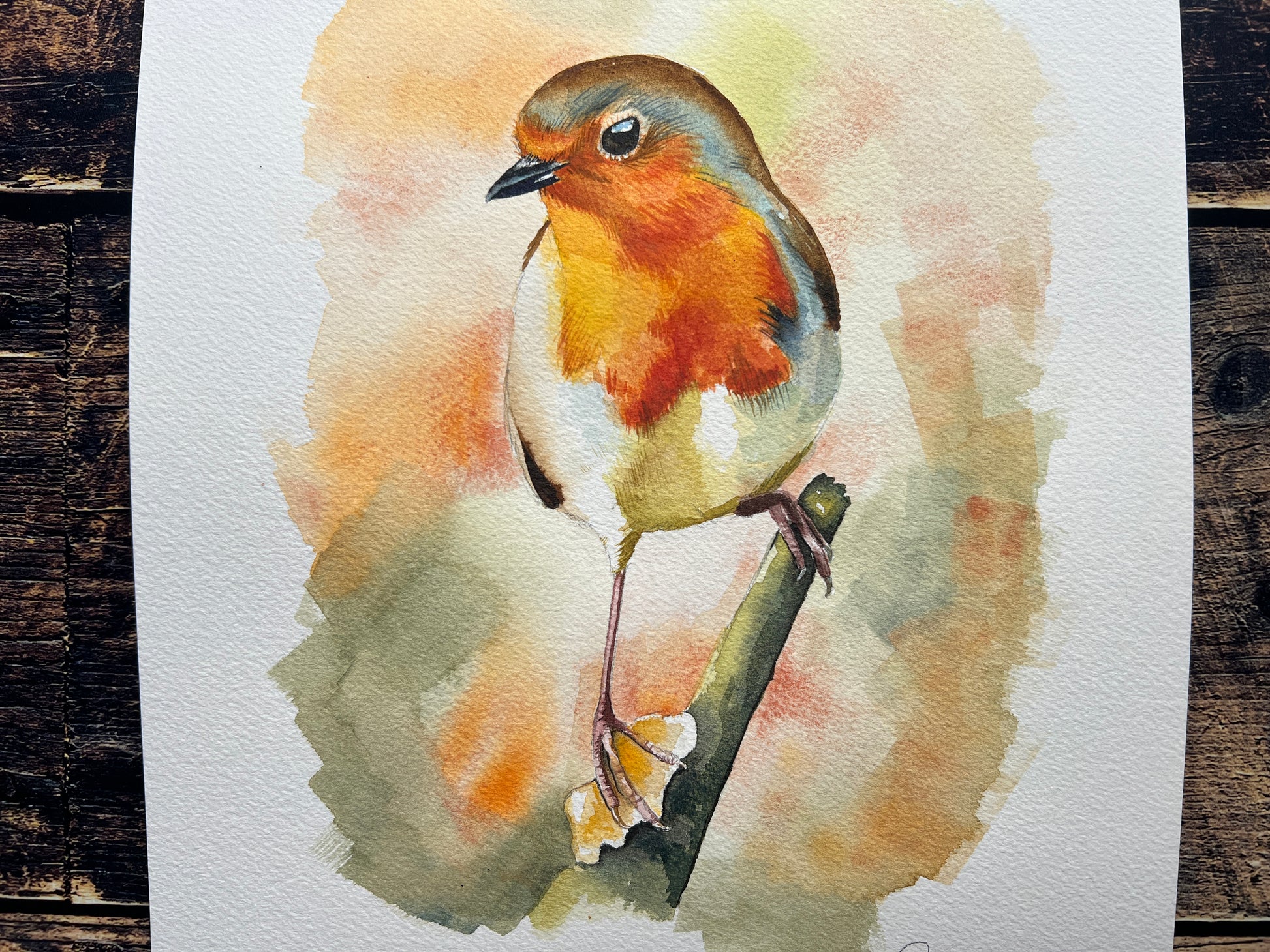 A watercolour painting of a robin, surrounded by blurry autumnal colours.