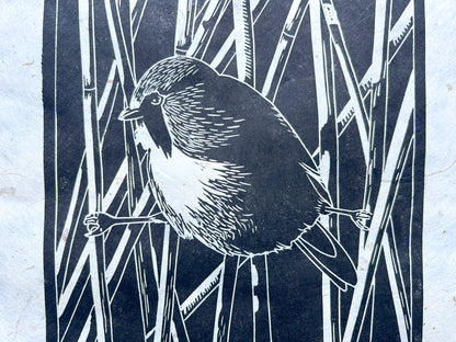 A close up of a bearded reedling black lino print on handmade mulberry paper