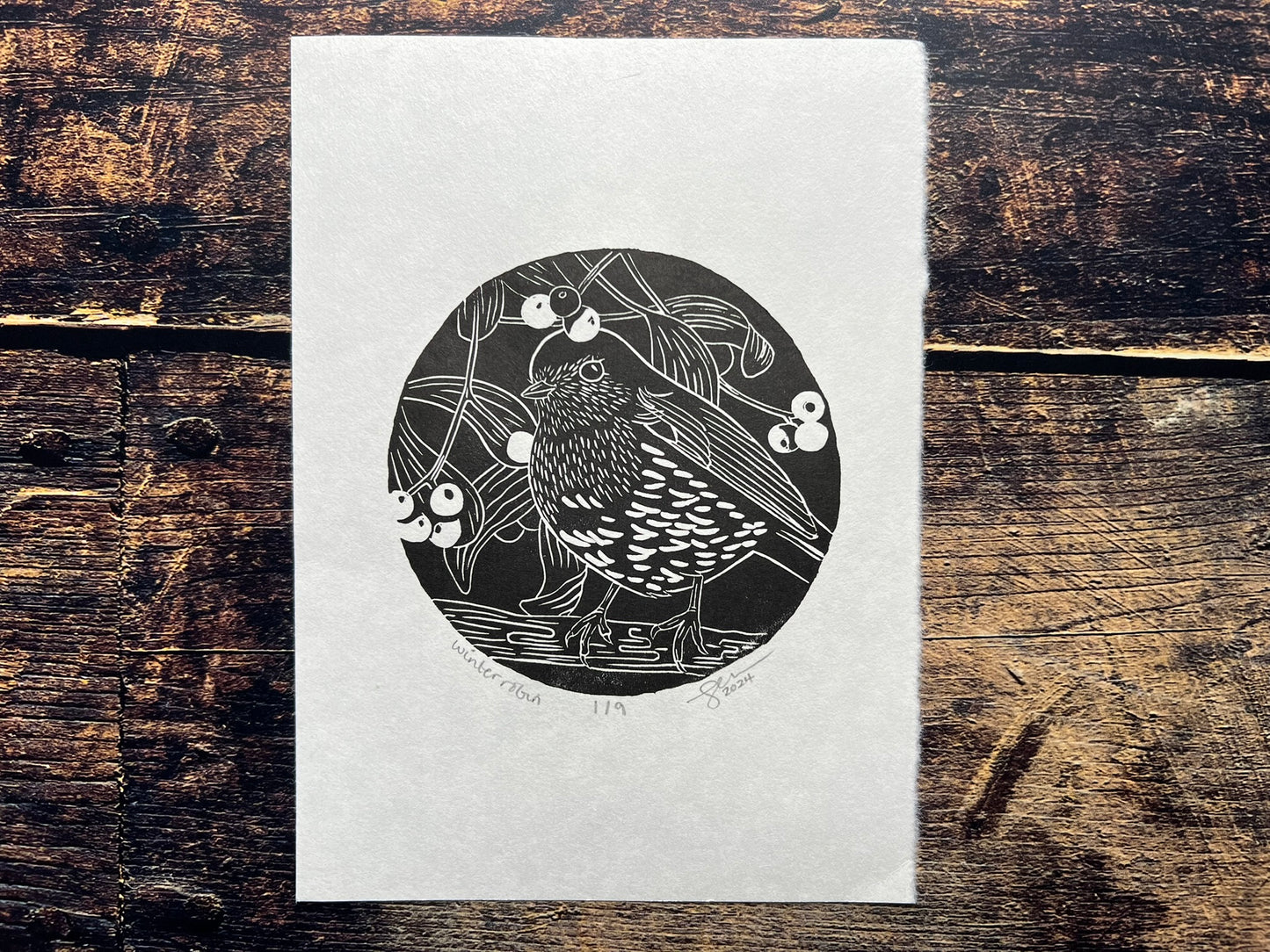 An A5 lino print of a robin surrounded by mistletoe