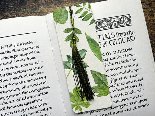 A photograph of a bookmark with British leaves on, photographed on an open book