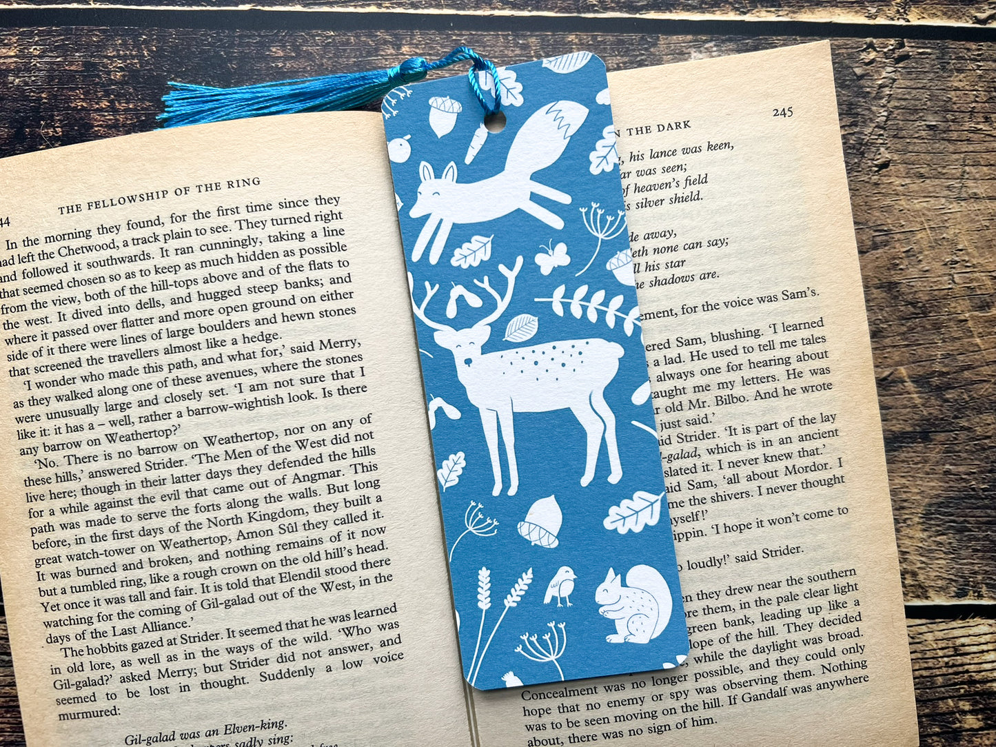A blue bookmark with white woodland animals on, photographed on an open book