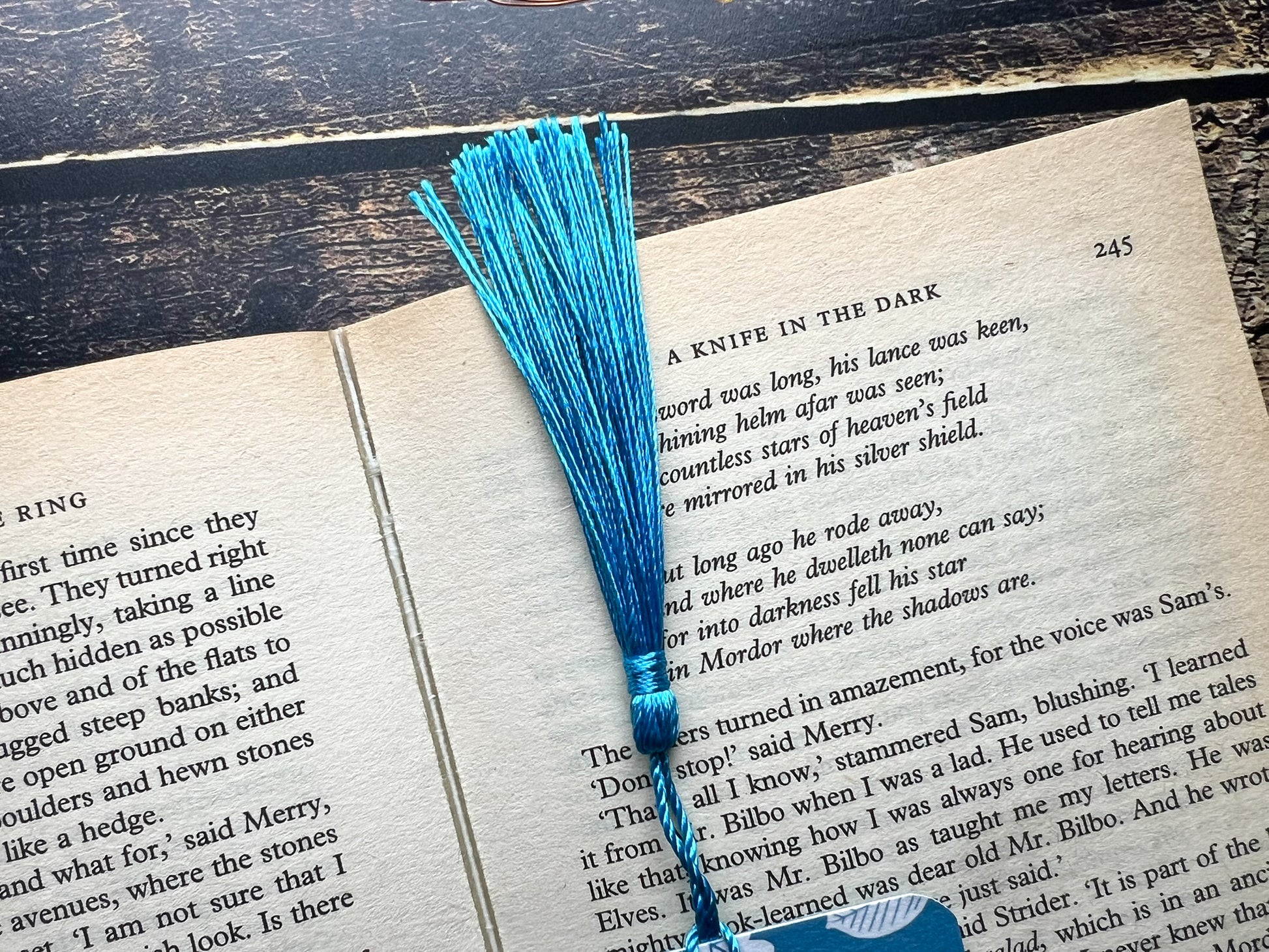 A blue bookmark with white woodland animals on, photographed on an open book