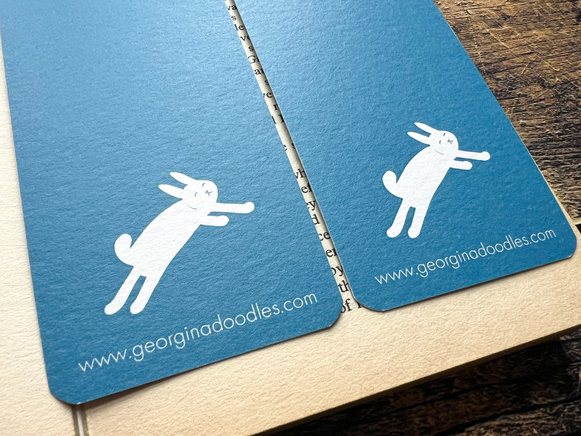 A blue bookmark with white woodland animals on, photographed on an open book