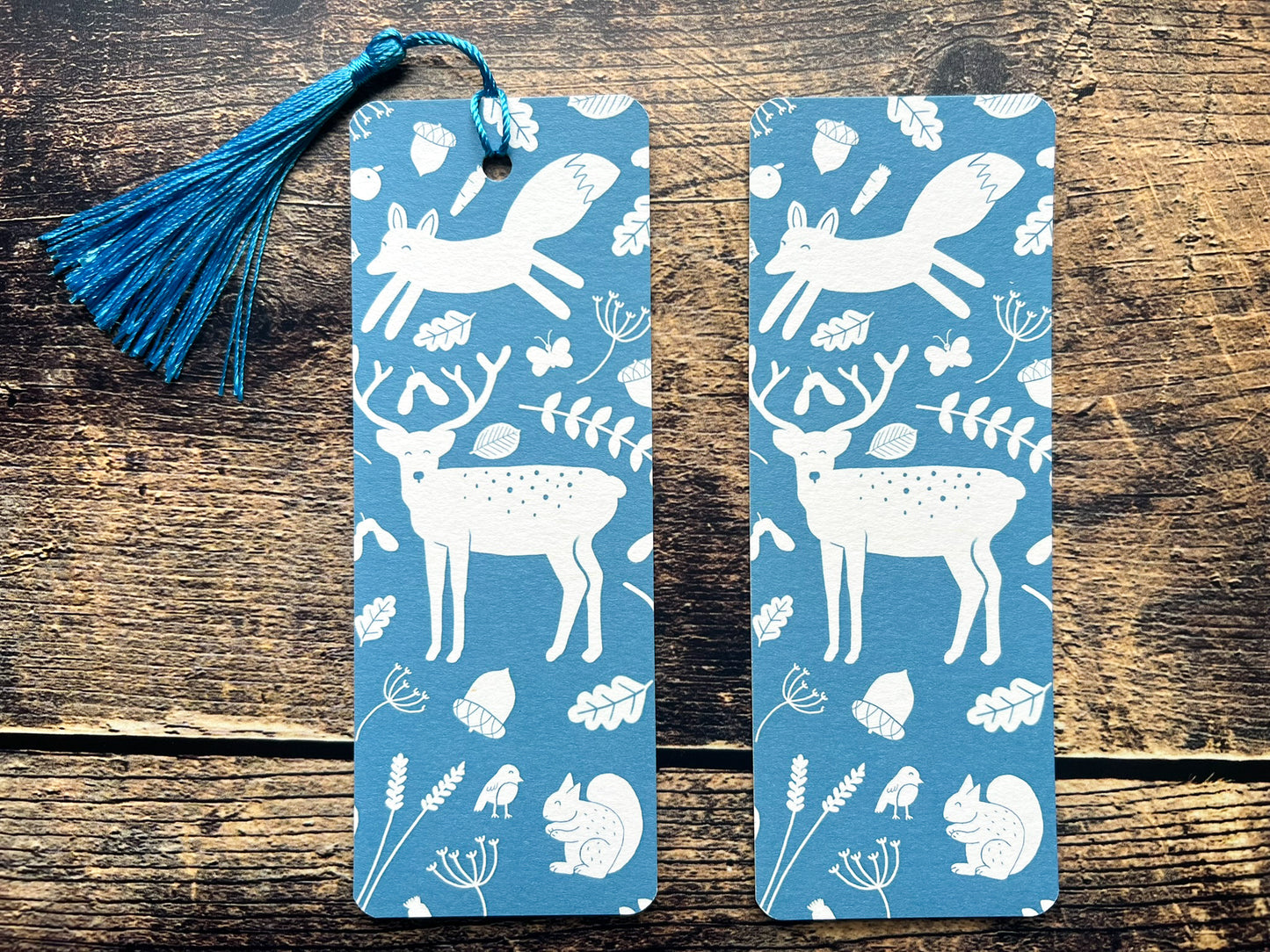 A blue bookmark with white woodland animals on, photographed on an open book