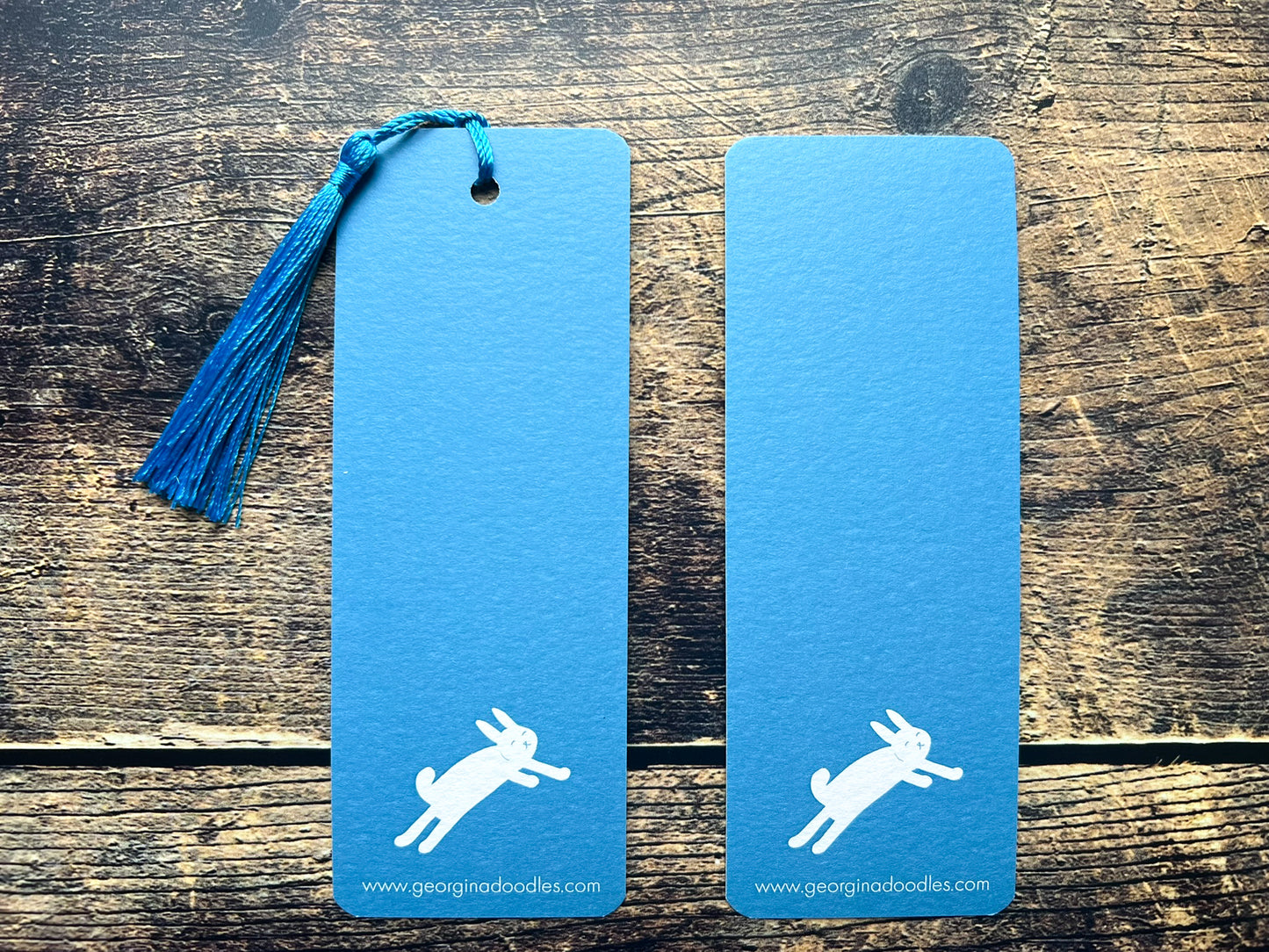 A blue bookmark with white woodland animals on, photographed on an open book