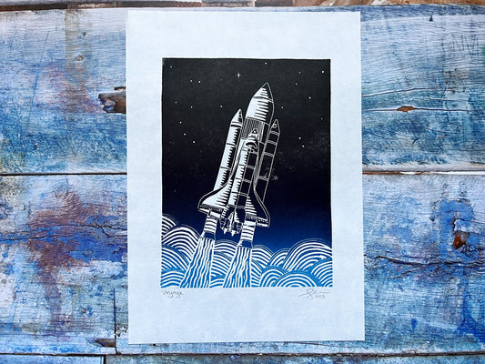 An A4 lino print with a light blue to black gradient or a space shuttled exiting earth's atmosphere