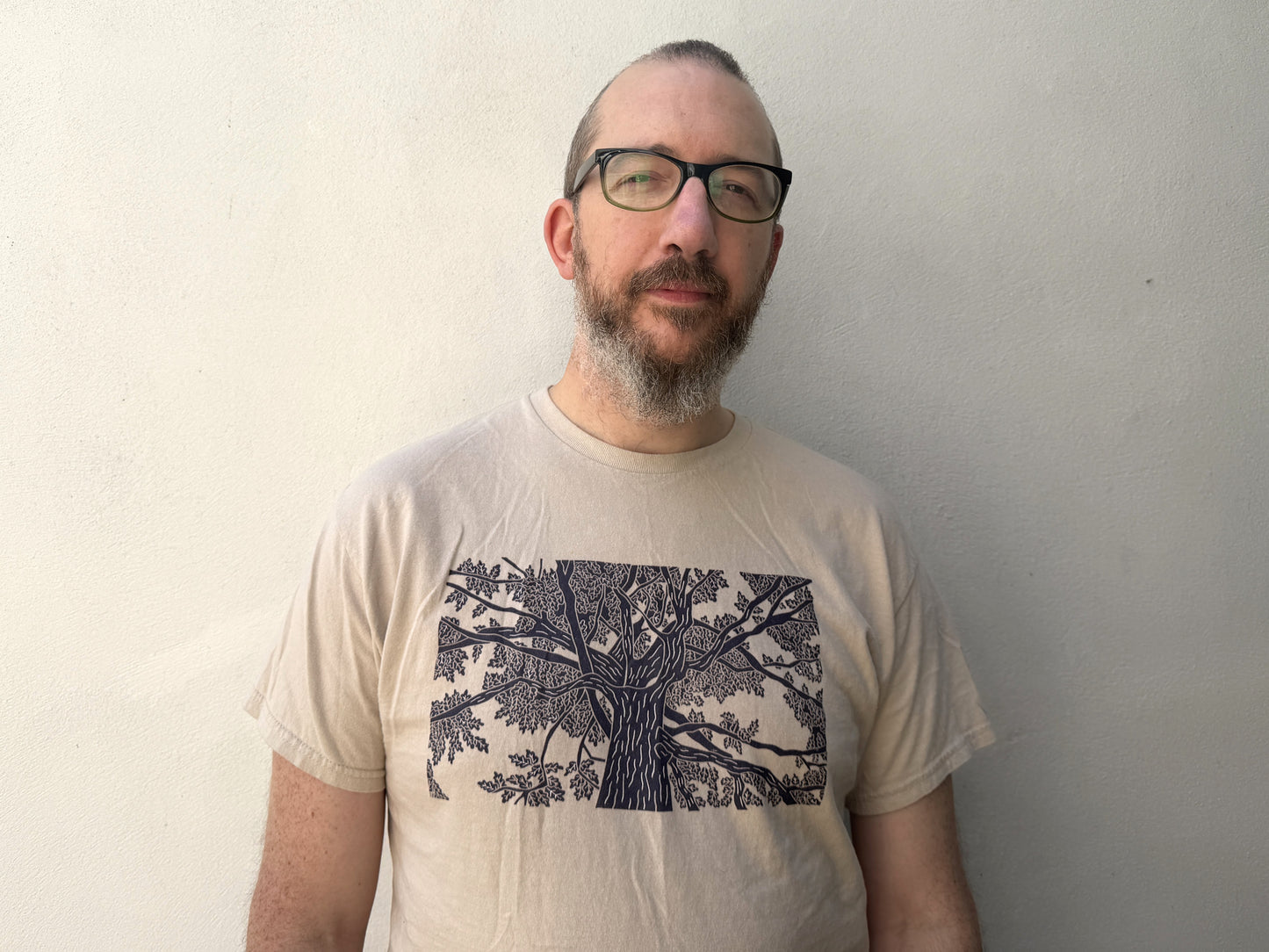 A photo of a man wearing a t-shirt with an oak tree lino print on the front