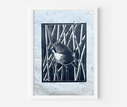 A black lino print of a bearded reedling on handmade mulberry paper