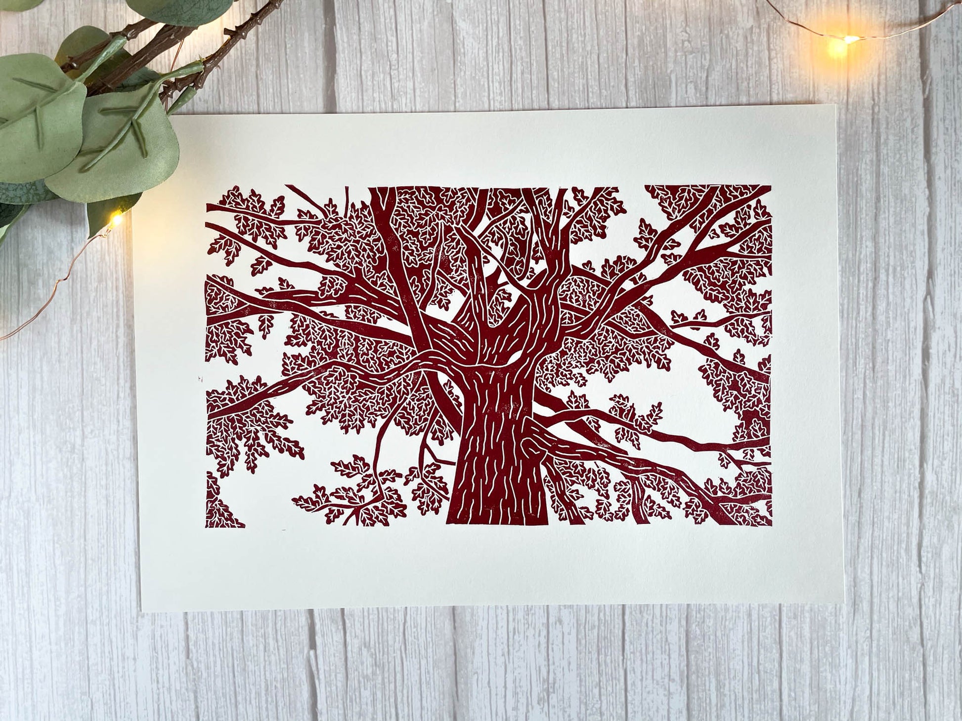 A lino print of an oak tree as viewed from standing under it and looking up in red