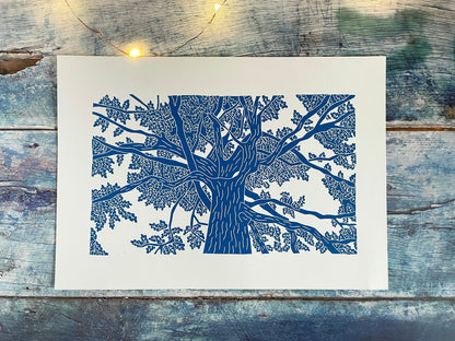 A lino print of an oak tree as viewed from standing under it and looking up in blue