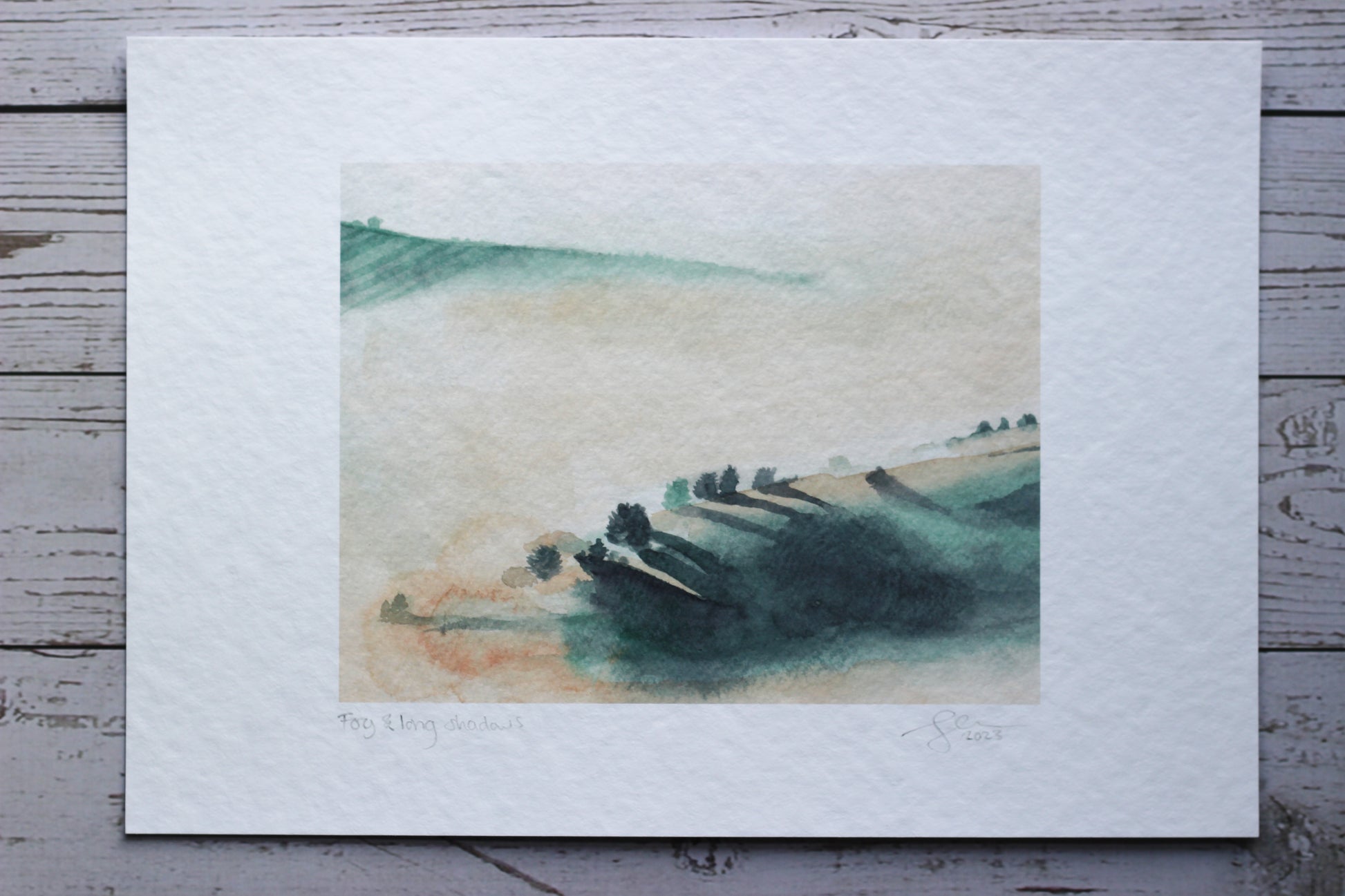 An A4 print of a foggy morning watercolour landscape with dramatic tree shadows