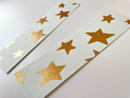A photo of two hand painted watercolour bookmarks with gold metallic watercolour stars