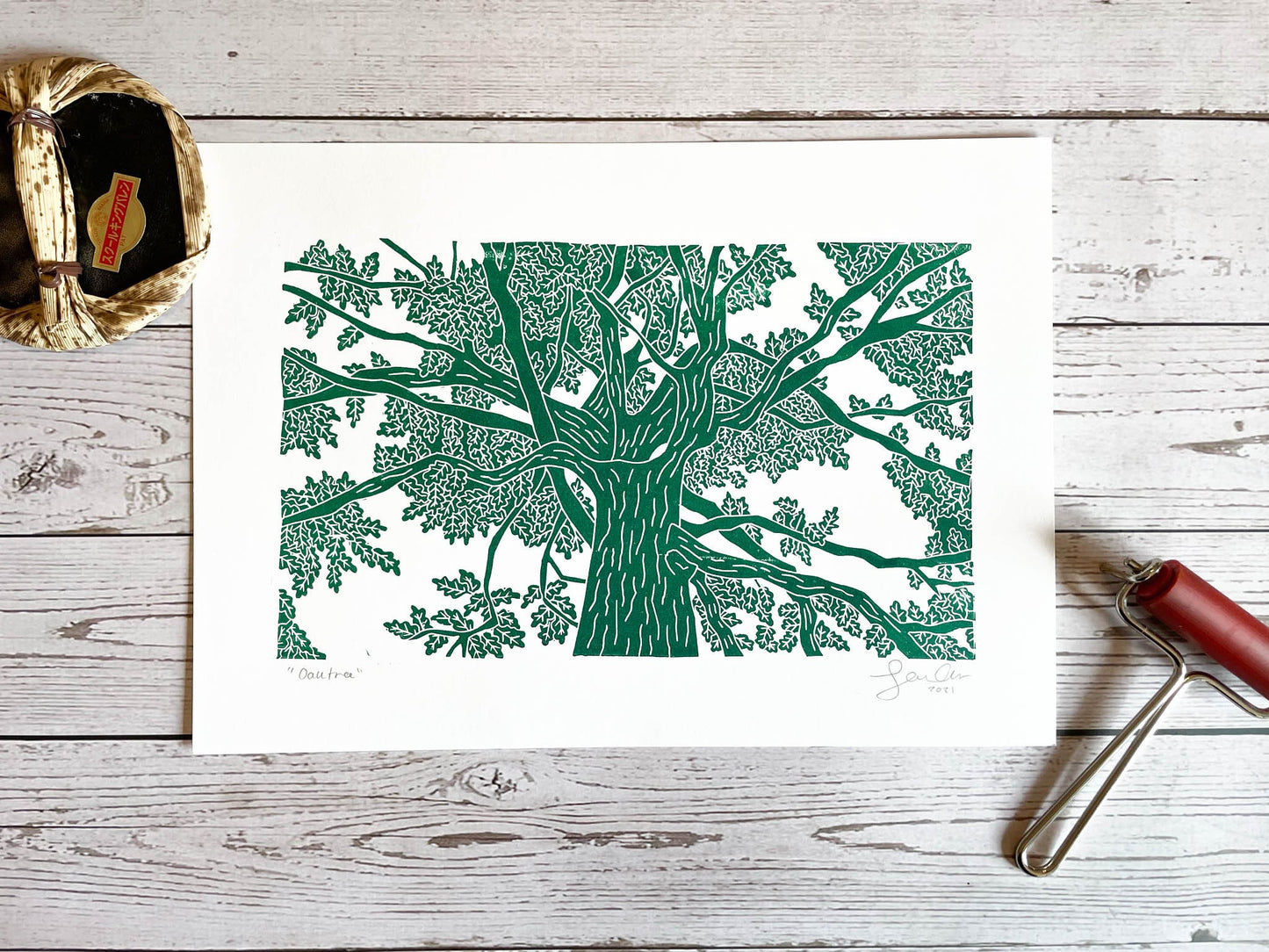 A lino print of an oak tree as viewed from standing under it and looking up in green