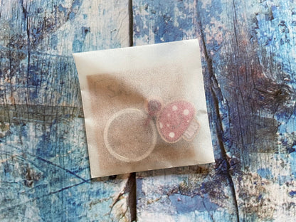 A photo of the mushroom keyring in a glassine bag