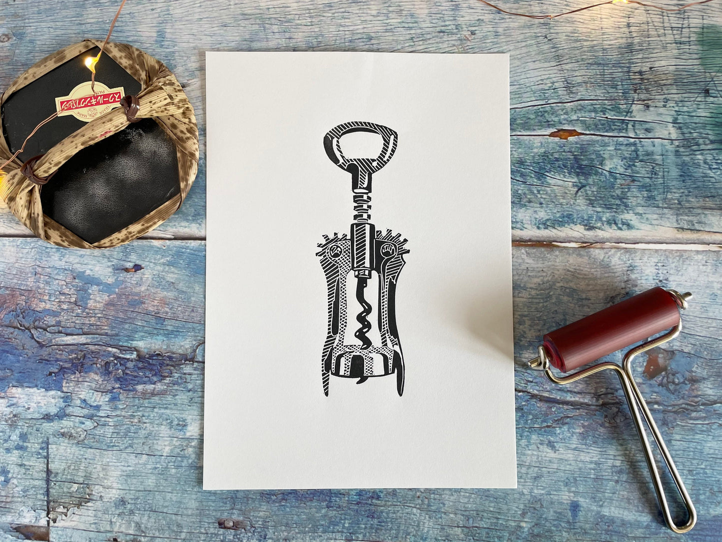 An A5 black lino print of a corkscrew bottle opener