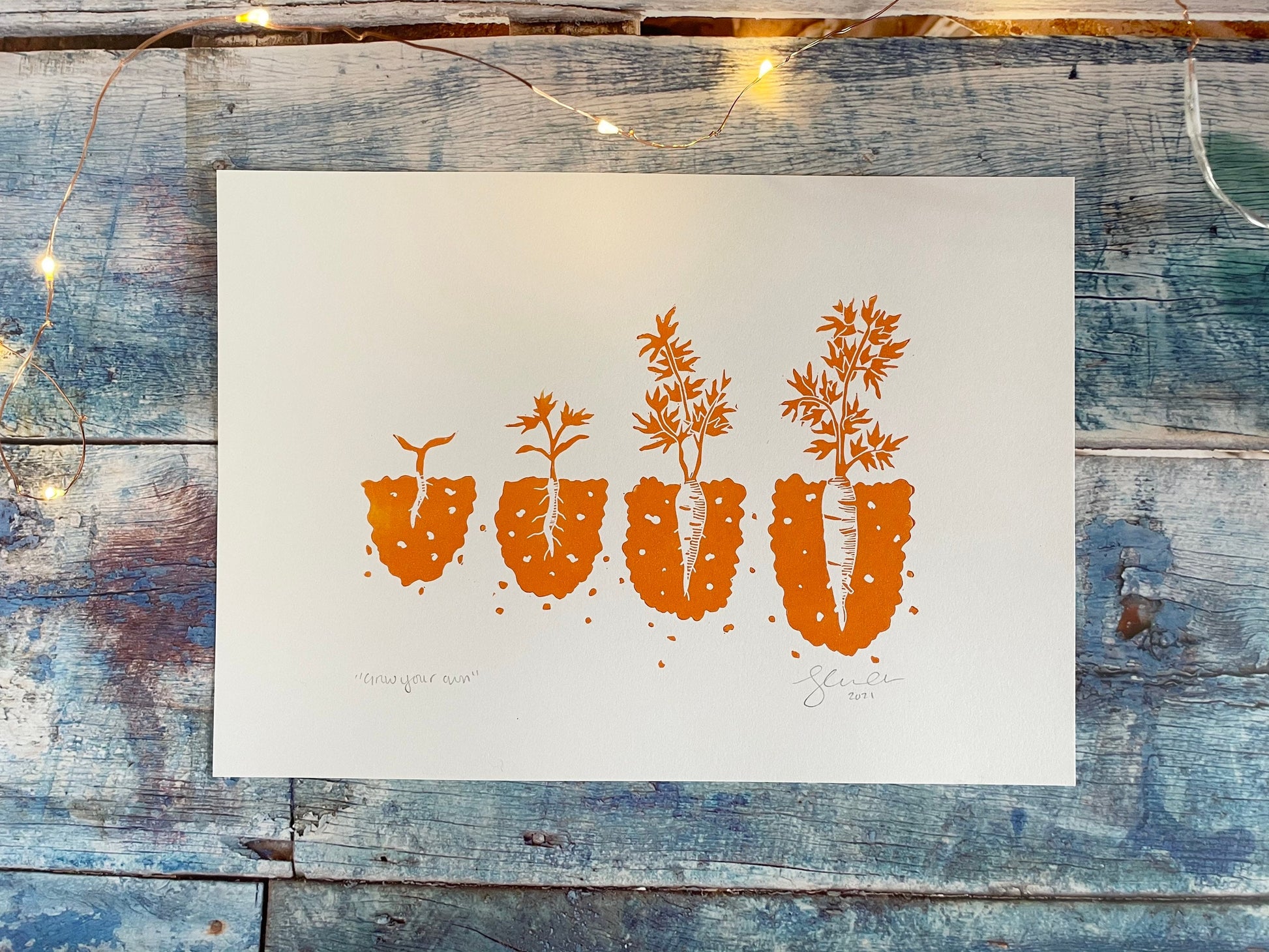 A lino print showing the different stages of a carrot growing from seedling to ready to pick in orange