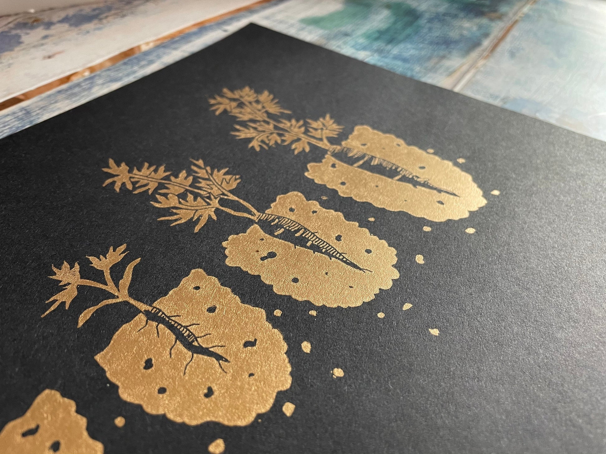 A lino print showing the different stages of a carrot growing from seedling to ready to pick in copper on black
