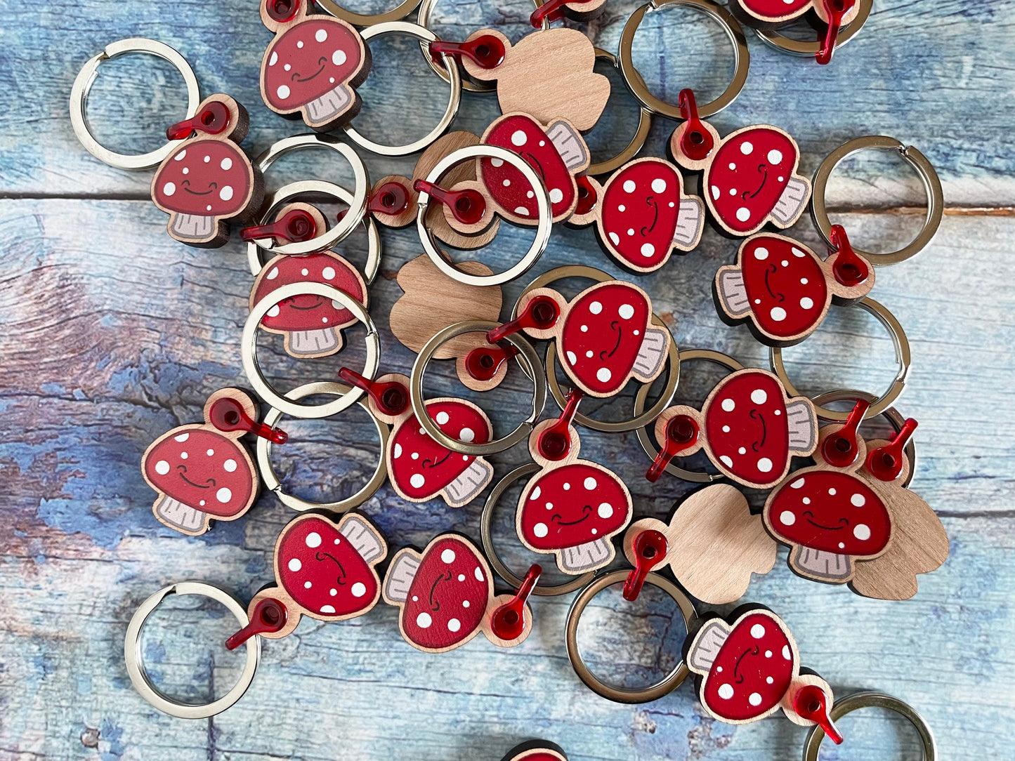 A picture of lots of cute red mushroom wooden keyrings made with cherry wood