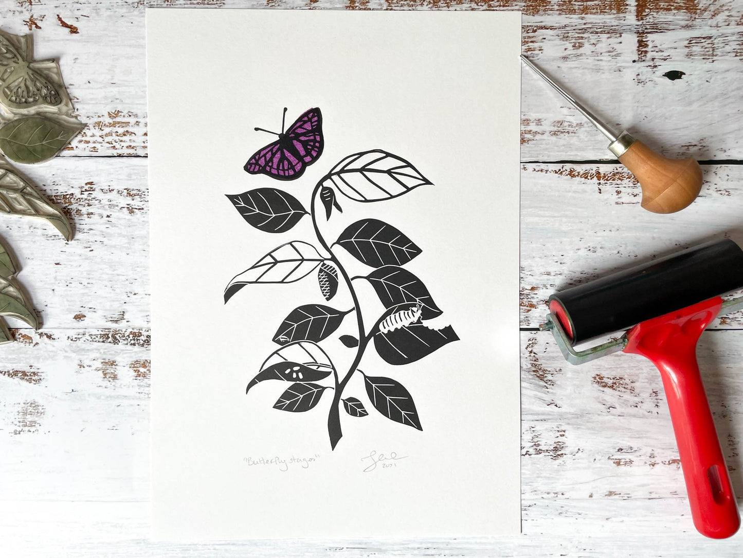 A lino print depicting the stages of a caterpillar turning into a butterfly while going up a vine