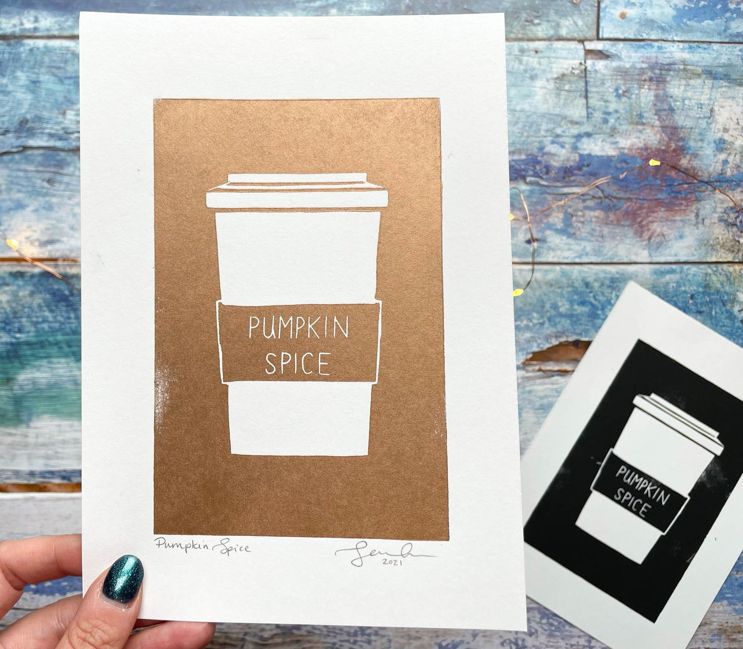 A simplistic lino print of a pumpkin spice latte in a takeout cup in copper