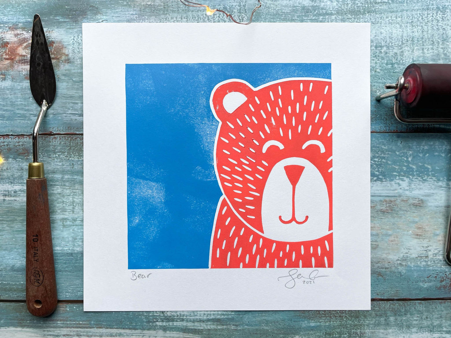 A multiblock lino print of a pink bear with a blue background