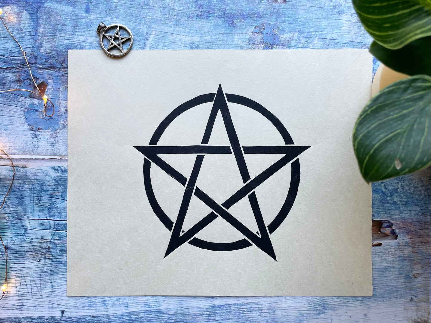 A simple black lino print of a pentagram in a circle