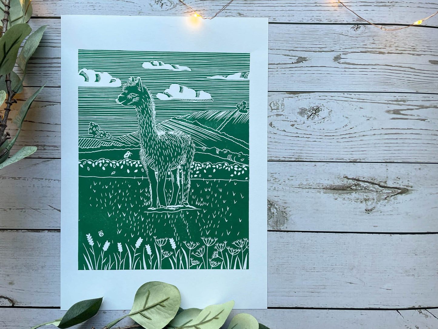 A green A4 lino print of a llama in a field