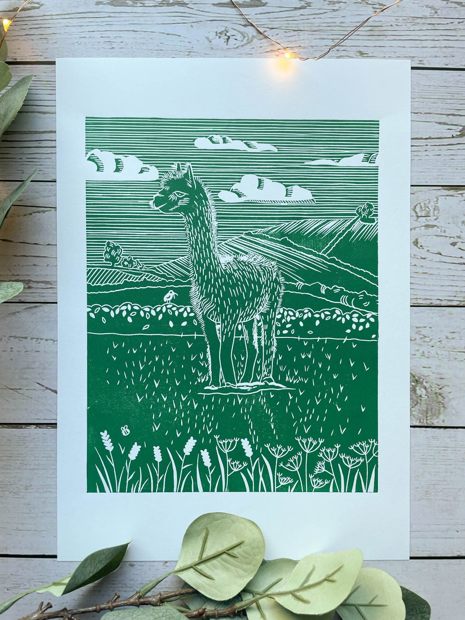 A green A4 lino print of a llama in a field