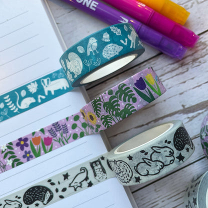 A set of three washi tapes stuck to paper with pens in the background