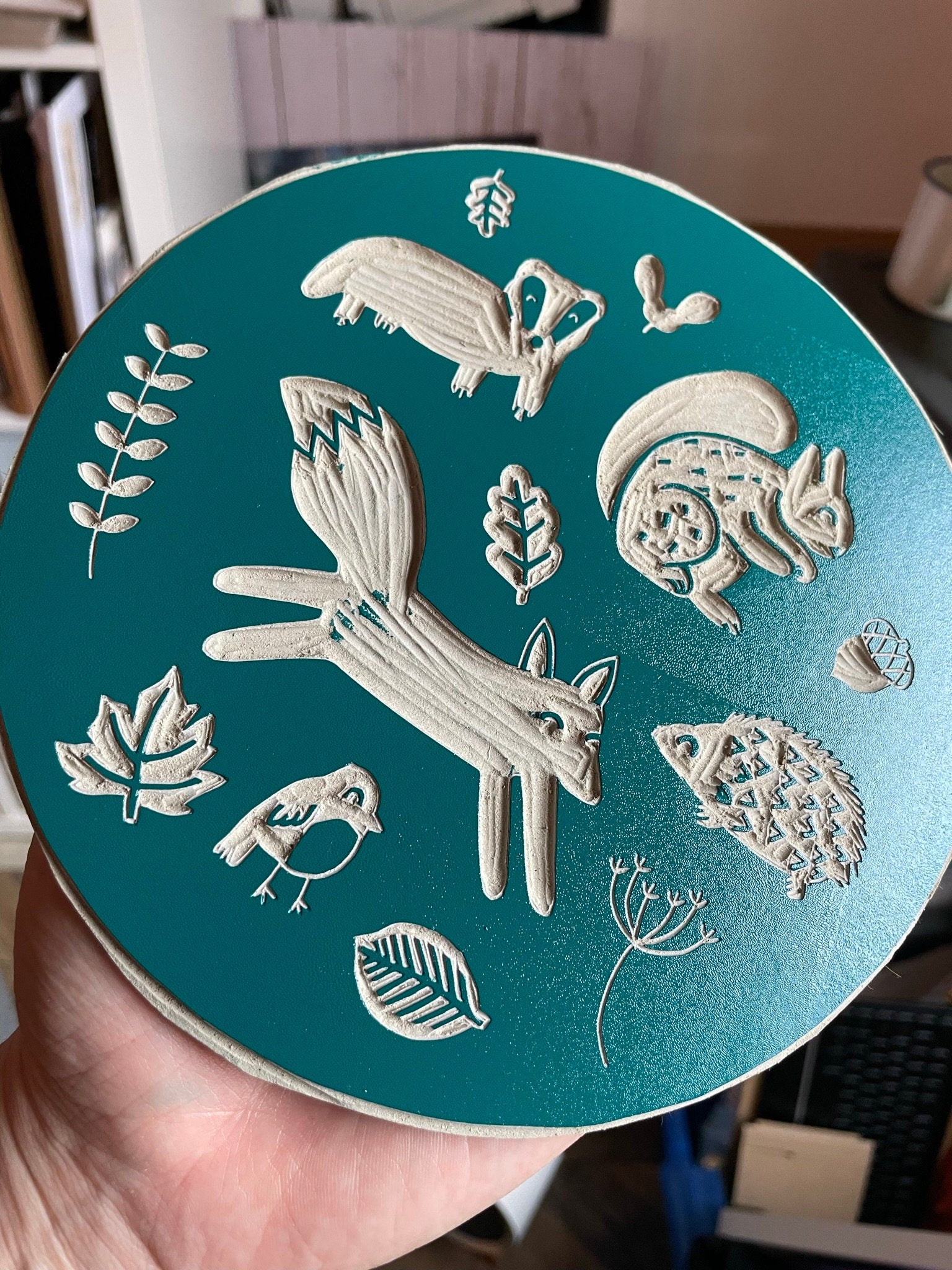A circular lino print in green on gorgeous handmade mulberry paper. The print has woodland animals on it and fauna.