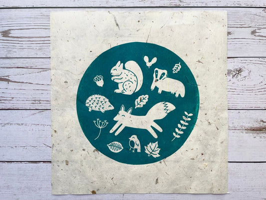 A circular lino print in green on gorgeous handmade mulberry paper. The print has woodland animals on it and fauna.