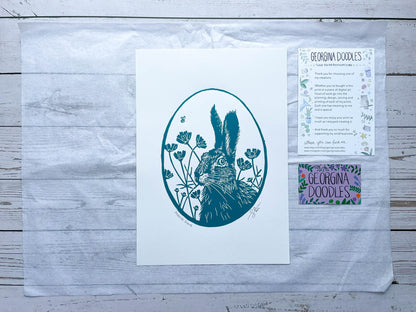 An oval lino print of a hare surrounded by flowers printed on A4 paper
